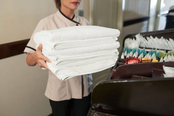 crop-chambermaid-with-pile-of-fresh-towels-2023-11-27-04-49-46-utc